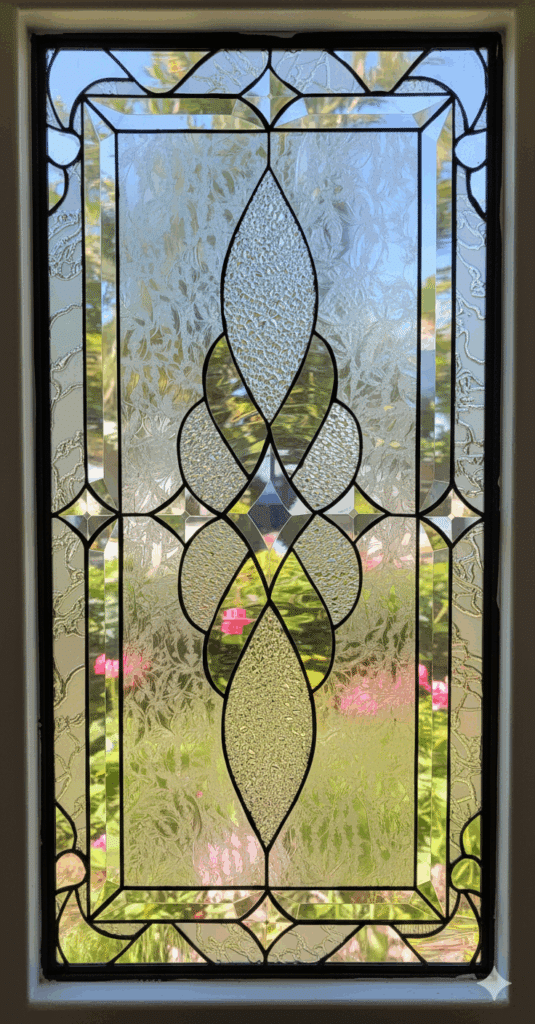 Rectangular clear stained glass panel with a symmetrical abstract design composed of various textured glass pieces and dark lead lines.