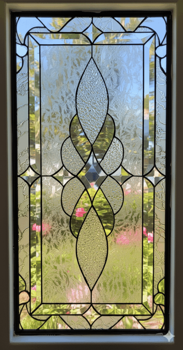 Rectangular clear stained glass panel with a symmetrical abstract design composed of various textured glass pieces and dark lead lines.