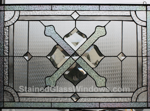 A rectangular leaded stained glass panel with a prominent central motif of clear beveled diamonds forming a square, intersected by two textured clear glass bands creating an 'X' shape. The panel features a geometric pattern of various clear textured and beveled glass pieces, including a patterned border and a background of fine textured clear glass, designed to provide privacy and brilliant light refraction.