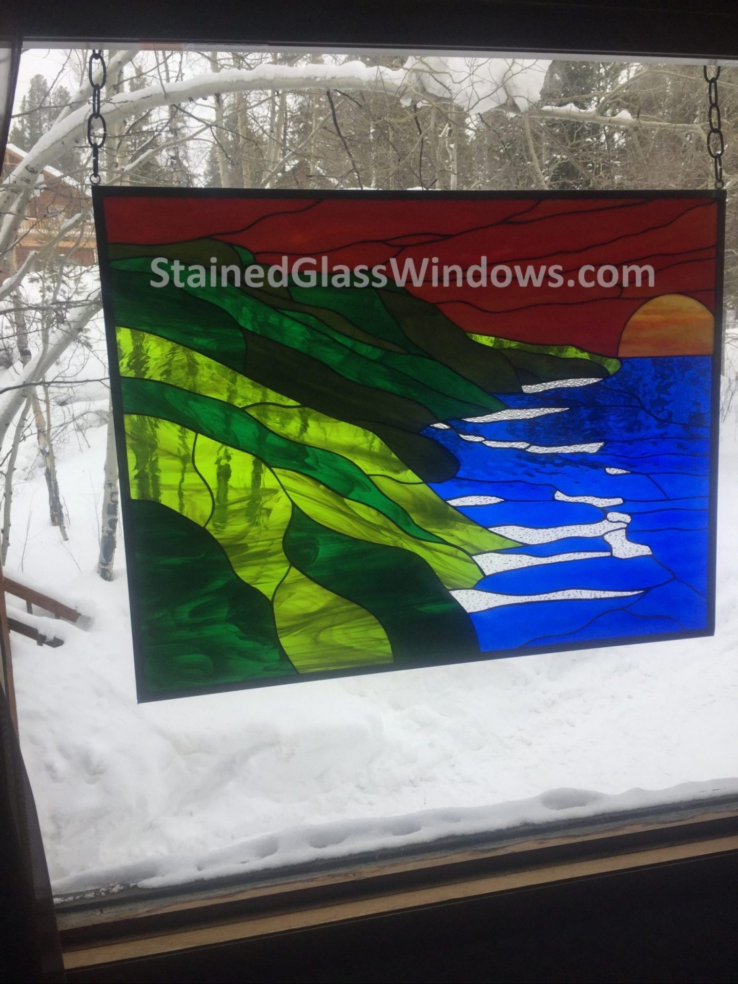 "Fire and ice" Hawaiian Coastline stained glass window hung with chains in snowy Colorado
