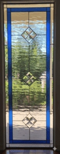 A tall, rectangular leaded stained glass panel featuring a vibrant sapphire blue border. The center consists of clear textured glass with three vertically aligned diamond-shaped bevel clusters.