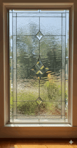 A rectangular, clear leaded stained glass window featuring a central beveled diamond design and smaller diamond accents, surrounded by textured privacy glass.