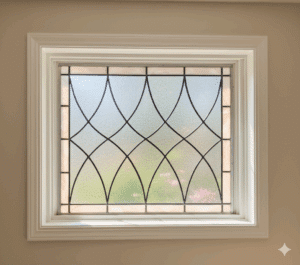 A rectangular stained glass panel with a classic, repeating pattern of curved, pointed oval shapes. The central design is made of clear, textured privacy glass and is framed by a simple border of off-white opalescent glass.