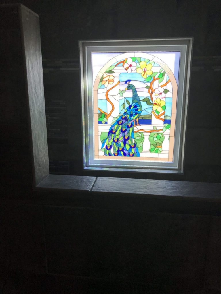 Framed and triple paned (Insulated) "Peacock & Magnolia Flowers" stained glass window installed in shower