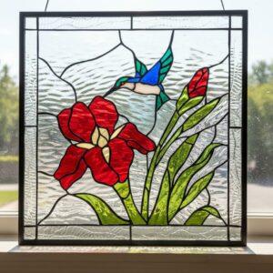 A square stained glass panel featuring a blue hummingbird, a red iris flower, and green foliage against a clear textured glass background.