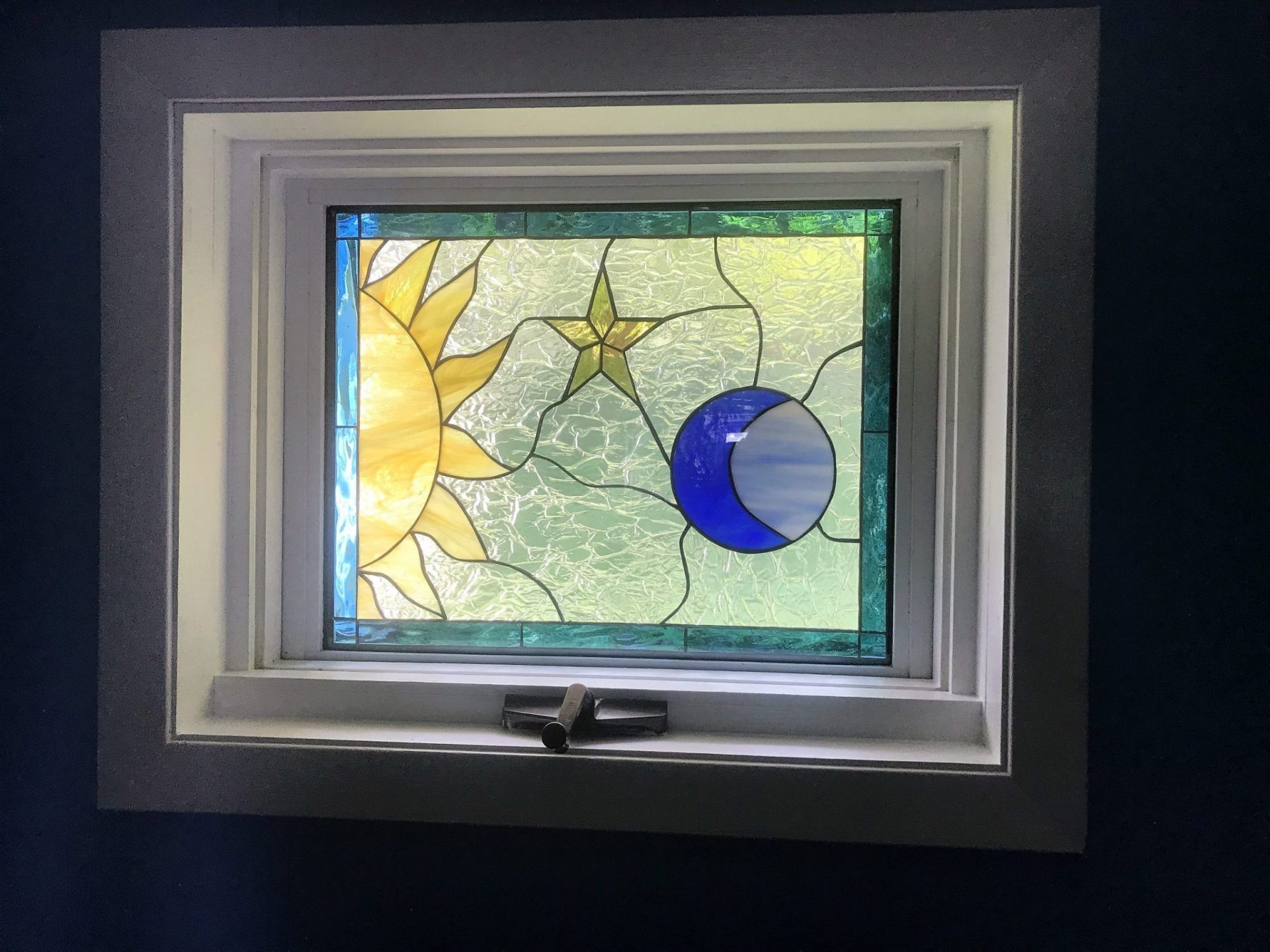 Mystical sun, moon, and star window installed in a crank-out vinyl frame