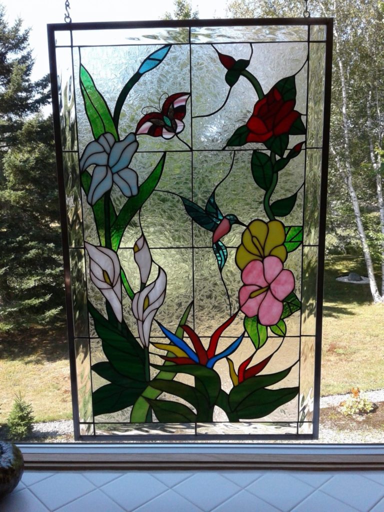 colorful hummingbirds and flowers stained glass panel hung in a kitchen window with chain