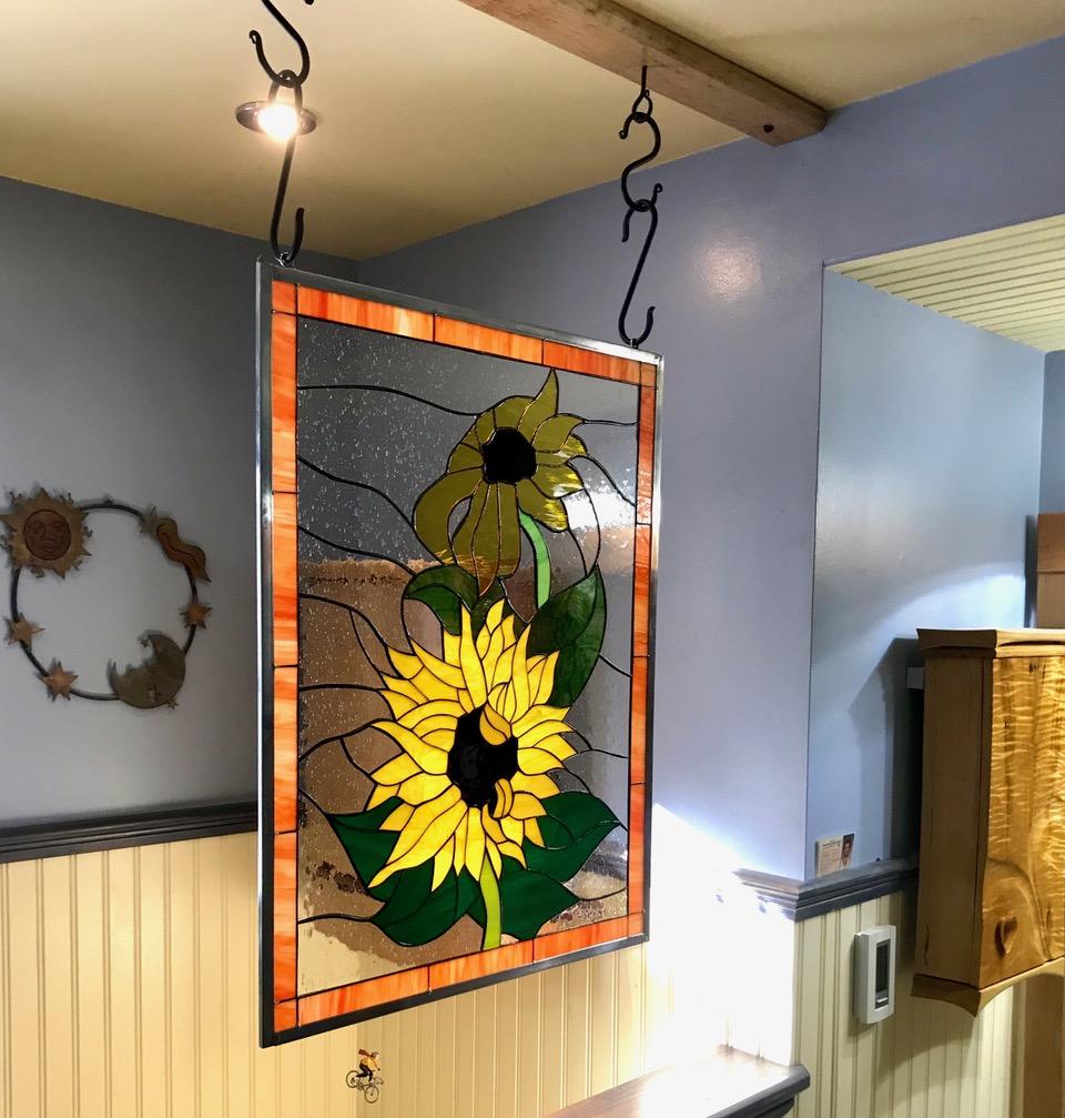 Stained glass sunflower window hanging by rustic hooks