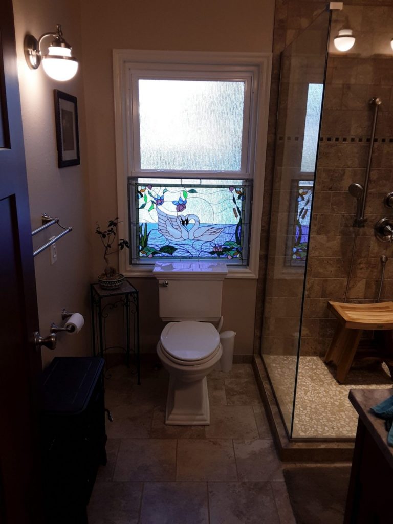 kissing swan stained glass window insert attached to the lower sash of a double hung window