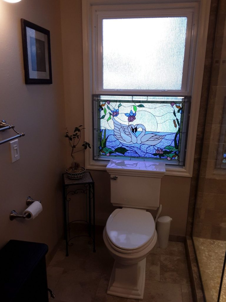 Beautiful kissing swan stained glass window insert attached to the lower sash of a double hung window