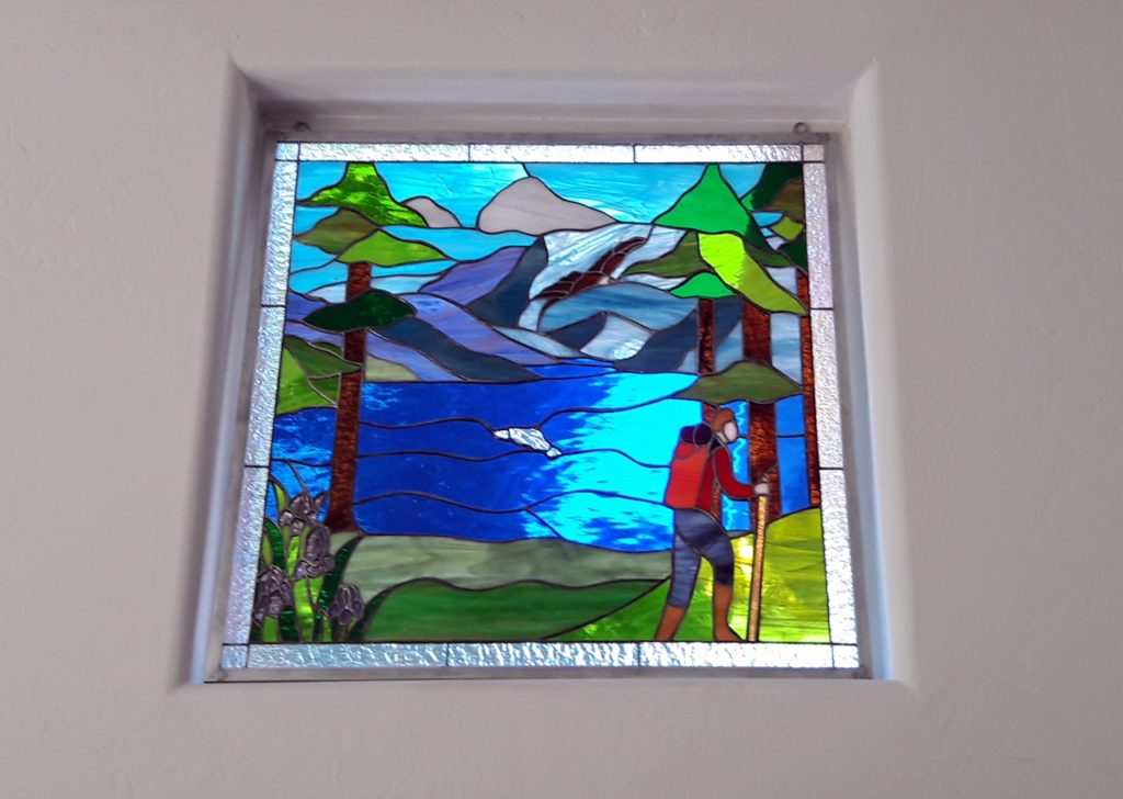 stained glass window hung with hooks in front of existing windows