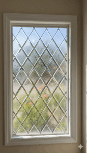 A rectangular stained glass window with a classic diamond lattice pattern. The diamonds alternate in a checkerboard pattern between clear beveled glass and frosty, textured 'glue chip' privacy glass.
