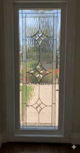 A tall rectangular clear leaded glass door insert featuring a central geometric pattern of interconnected diamond-shaped bevels and surrounding varied textured clear glass.