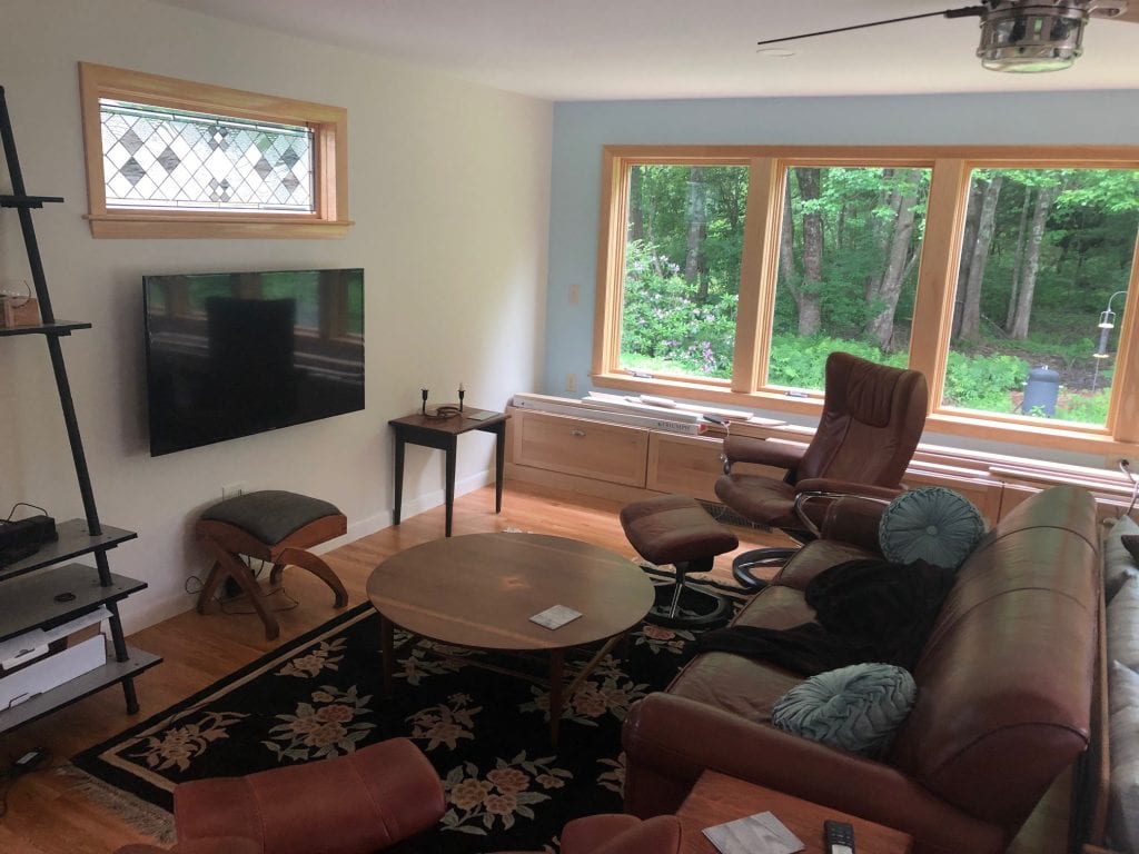 A rectangular stained glass transom window panel featuring a clear geometric diamond pattern made of beveled and textured glass, set in a natural wood frame above a television.