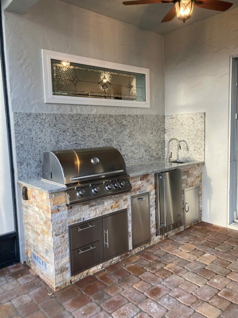 A horizontal rectangular transom window featuring a clear, leaded stained glass panel with beveled diamond patterns and textured glass, set in a white frame above an outdoor kitchen.