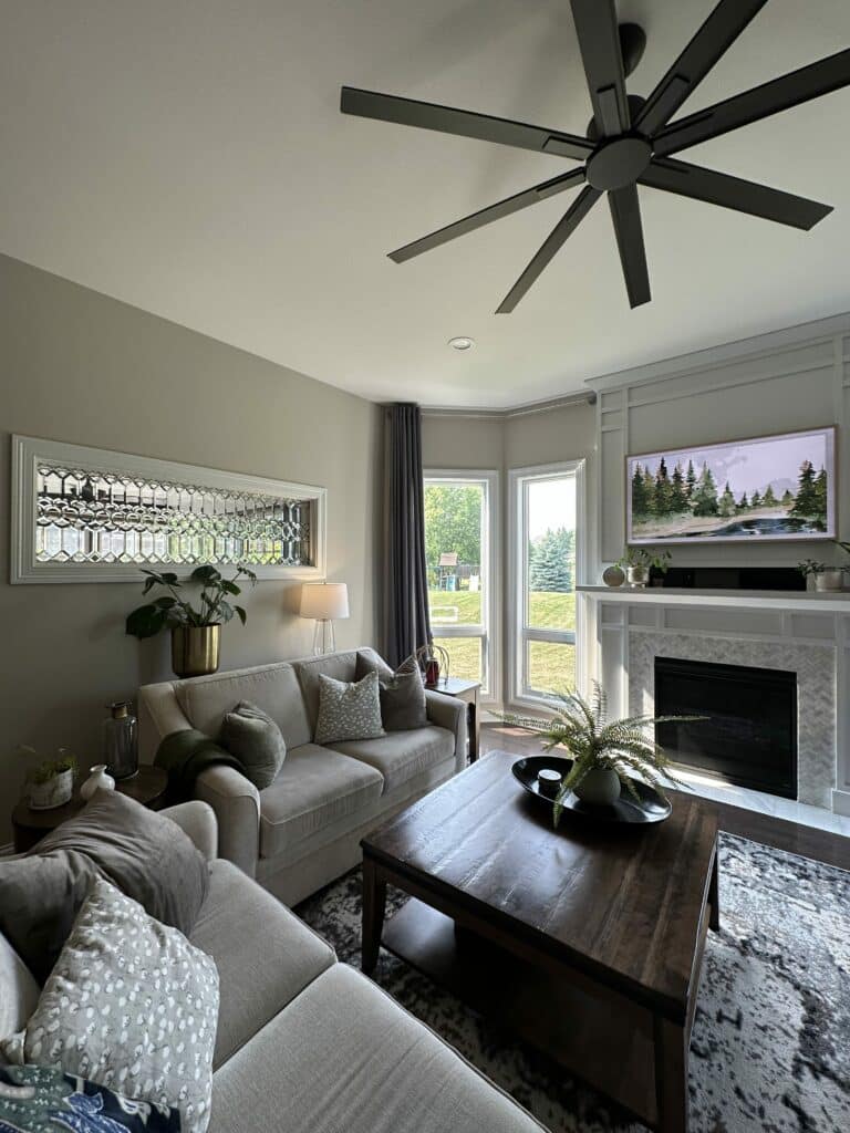 A rectangular clear beveled stained glass transom window panel featuring an intricate geometric pattern of interlocking circles and faceted shapes, set within a crisp white frame, installed above a light-colored sofa in a modern living room.