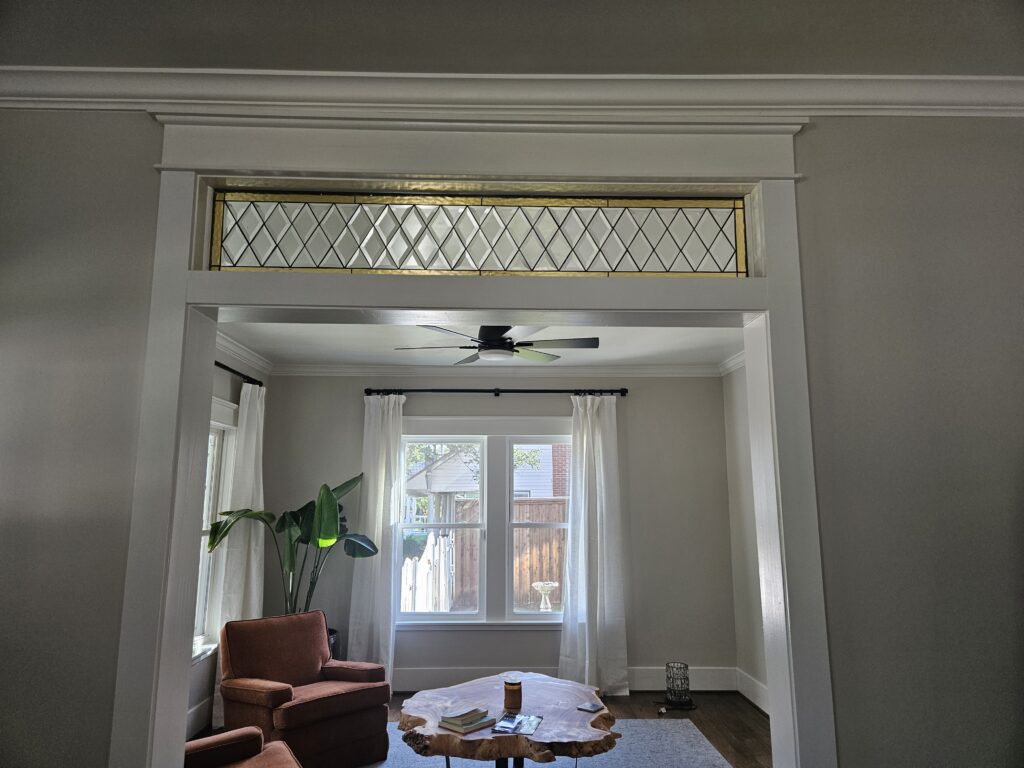 A rectangular stained glass transom window featuring clear beveled diamond shapes and textured gold glass borders, installed above an interior doorway.