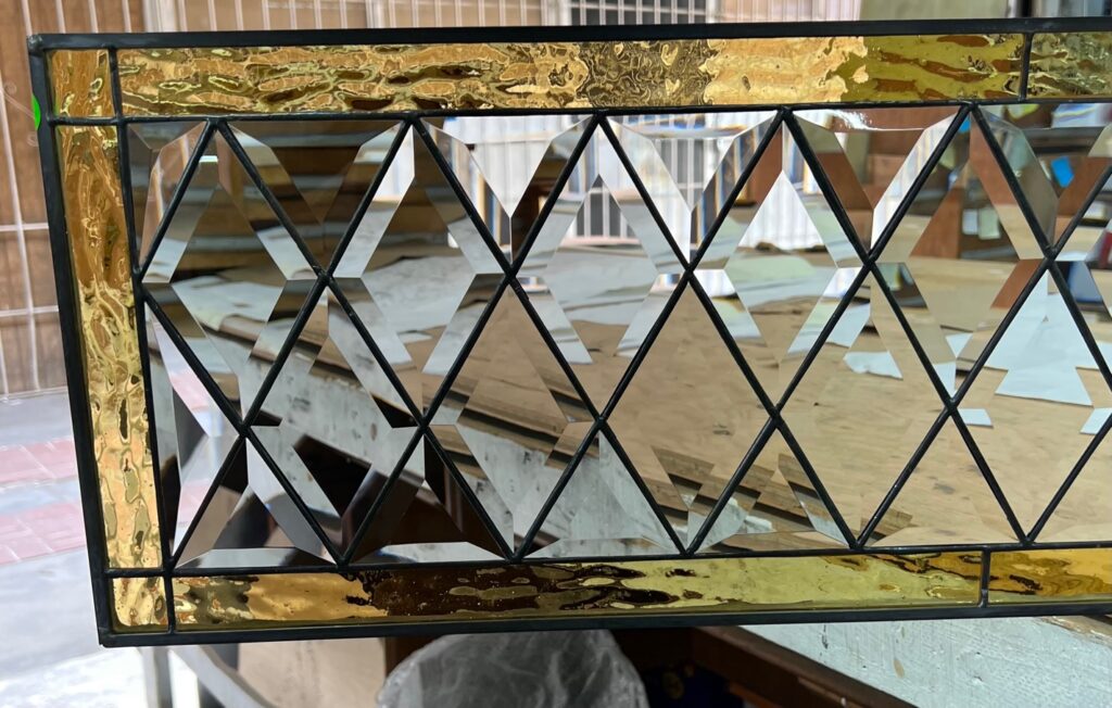 A rectangular leaded stained glass panel featuring a center of clear beveled diamonds bordered by textured gold glass on the top, bottom, and sides.