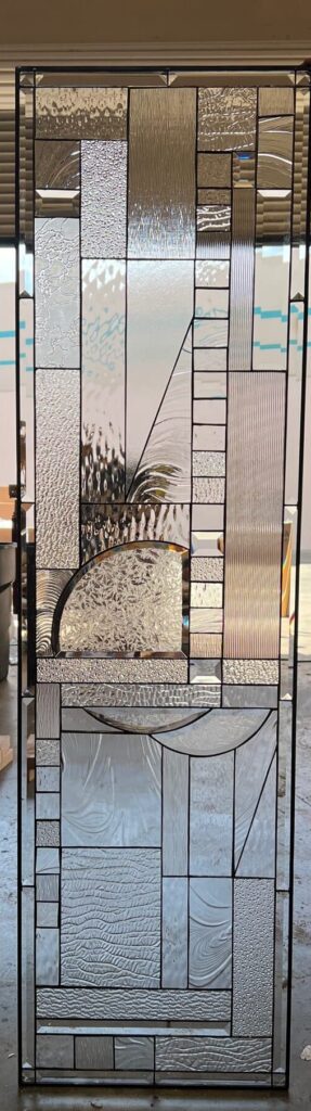 A rectangular leaded stained glass panel featuring an abstract design composed of various clear textured glass and sparkling clear bevels.