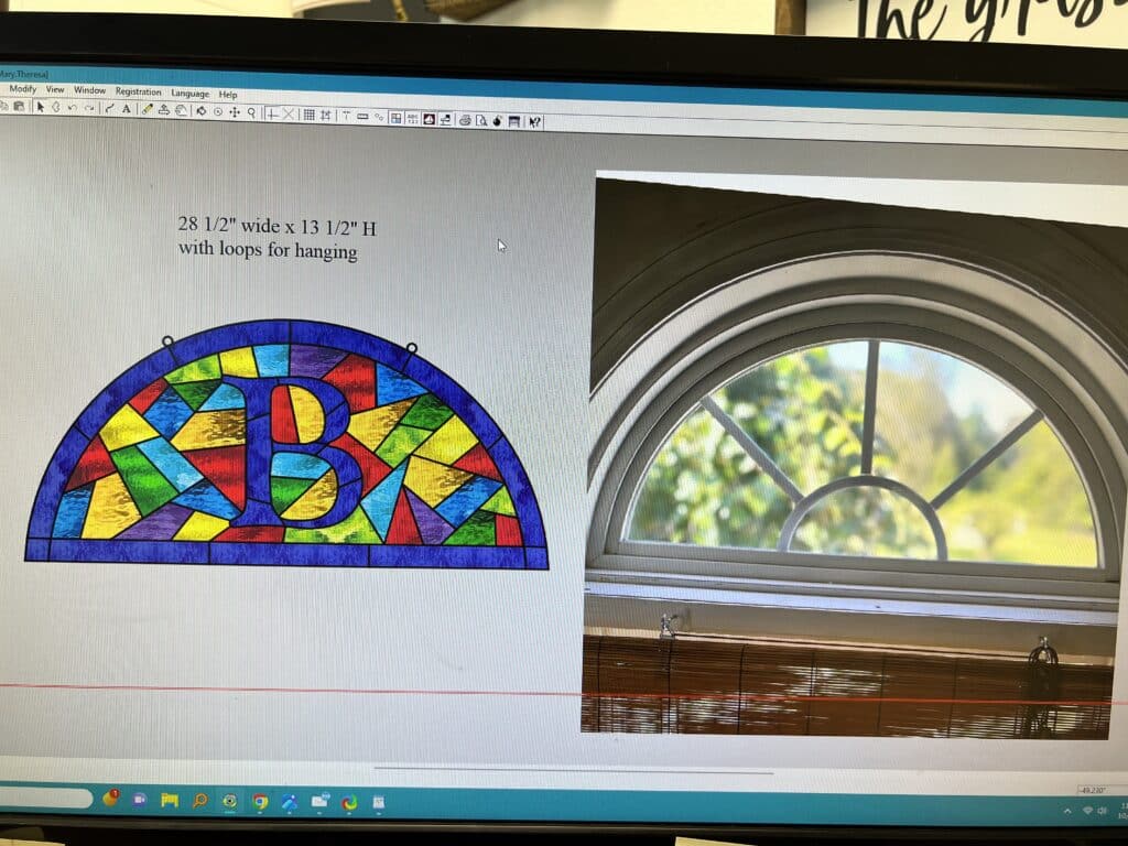 A colorful 28 1/2 x 13 1/2 inch arched stained glass panel design featuring a large central initial 'B' surrounded by geometric pieces in various shades of red, yellow, green, blue, and purple, with two hanging loops at the top.