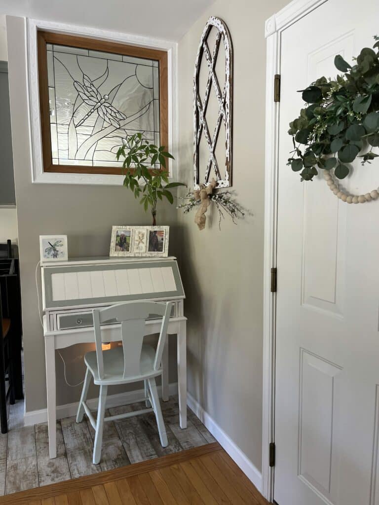 A rectangular, wood-framed clear stained glass window panel featuring a large, textured glass dragonfly with intricate wings, set against a background of wavy clear textured glass resembling water or reeds.