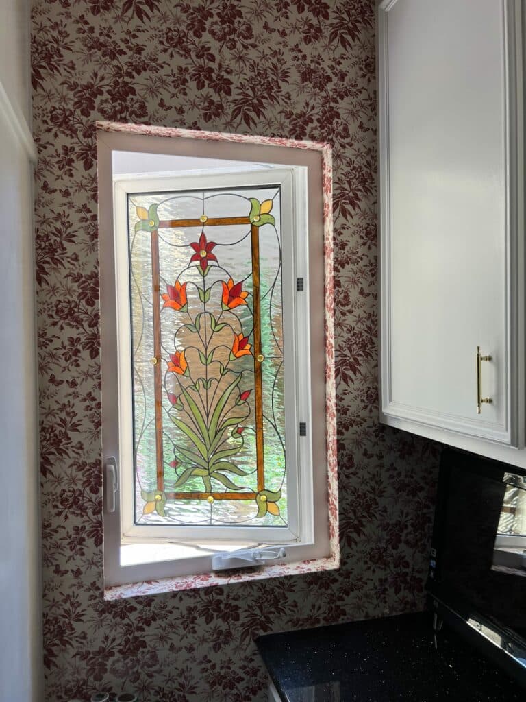 Stained glass floral design, sealed within tempered glass, in a vinyl casement frame