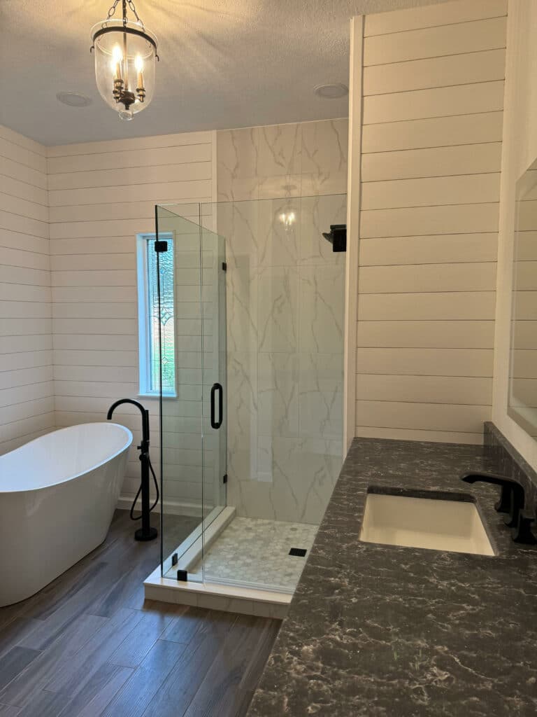 A rectangular stained glass window featuring clear textured and beveled glass in a geometric pattern, set within a modern glass-enclosed shower with shiplap walls.