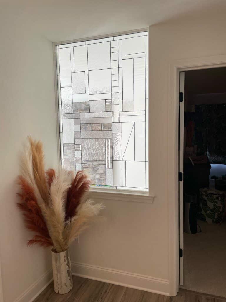 A rectangular, leaded clear textured glass window featuring an abstract geometric pattern.