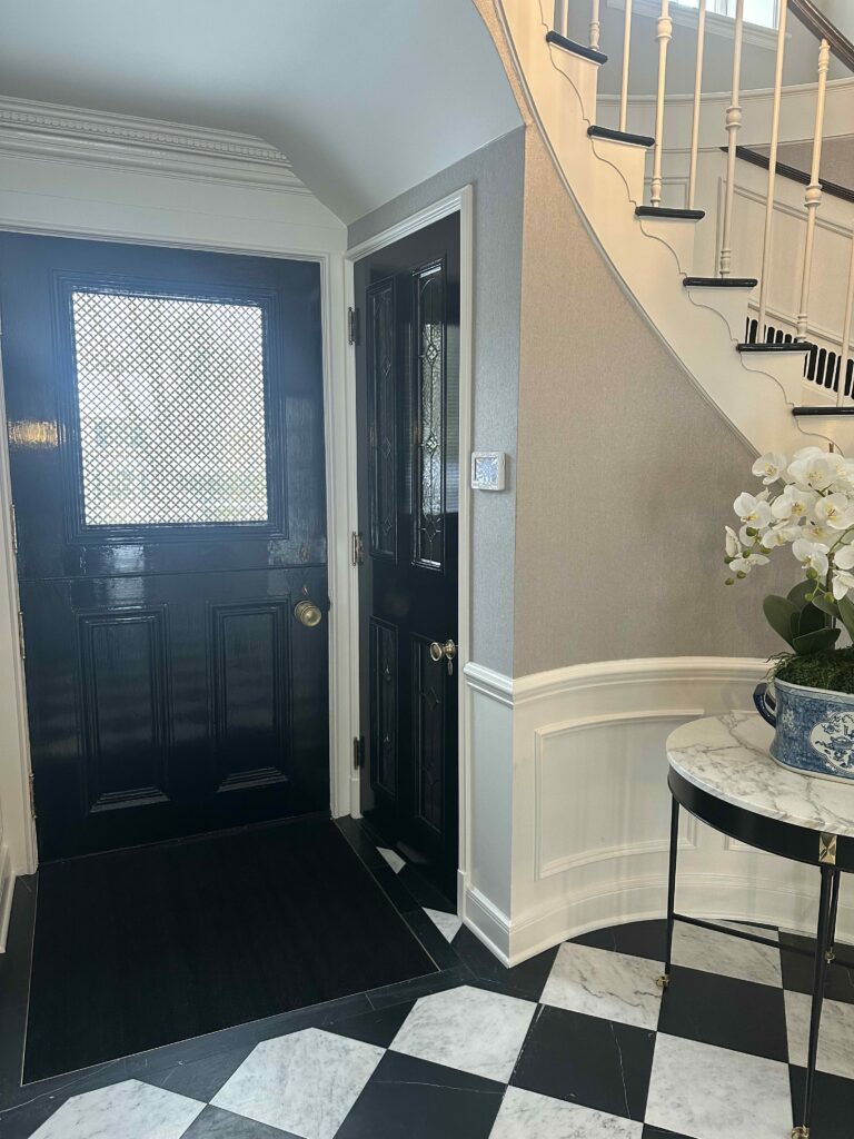 A black entry door features clear, geometrically patterned beveled glass panels, enhancing light and privacy in a home foyer.