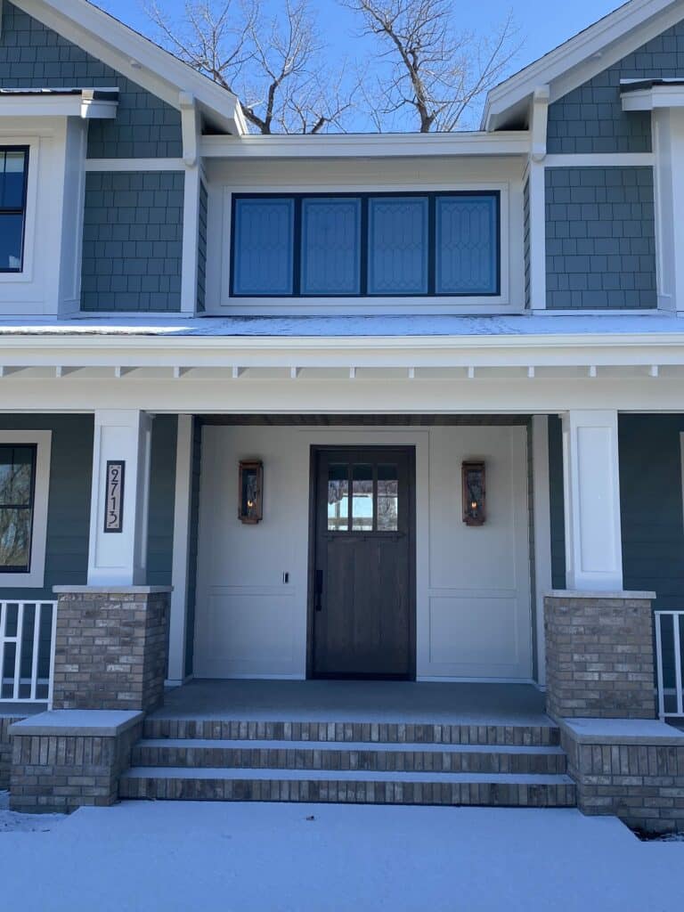A horizontal row of four rectangular transom windows above a dark wood front door, featuring a clear geometric leaded glass pattern.