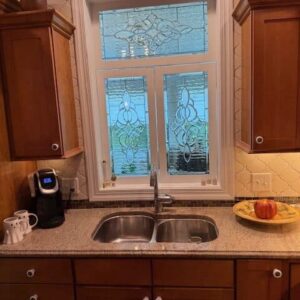 Multi-Panel Rectangular Clear Beveled Stained Glass Window with Decorative Scrollwork A multi-panel rectangular, leaded clear beveled stained glass window with ornate scrollwork designs, installed above a kitchen sink.