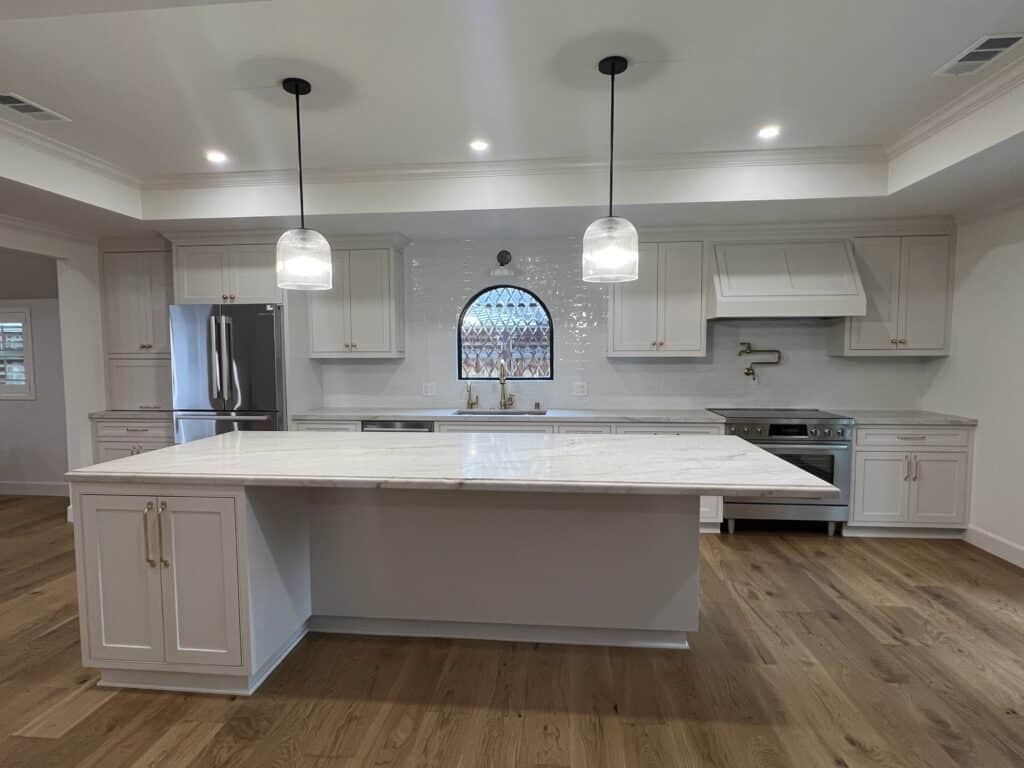 An arched, clear beveled stained glass window featuring a diamond pattern, installed above a kitchen sink.