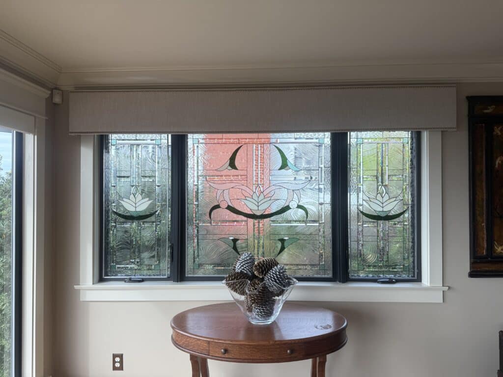 Three rectangular stained glass window panels, installed side-by-side, depicting stylized white lotus flowers and organic green leaves amidst clear textured and beveled glass, framed in dark metal.