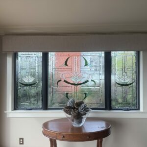 Rectangular Three-Panel Stylized Lotus Stained Glass Window Three rectangular stained glass window panels, installed side-by-side, depicting stylized white lotus flowers and organic green leaves amidst clear textured and beveled glass, framed in dark metal.