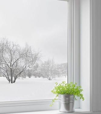 A rectangular, leaded stained glass panel depicting a snowy winter landscape with bare trees and white textures.