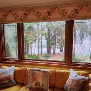 Rectangular Leaded Diamond Grid Stained Glass Panels Two rectangular, leaded stained glass panels featuring a clear, textured diamond grid pattern flank a large clear window looking out onto trees and water. The panels are set within a wooden window frame.