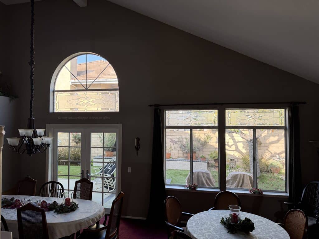 An arched transom leaded stained glass panel featuring clear textured and beveled glass in an abstract curvilinear design, installed above white French doors.
