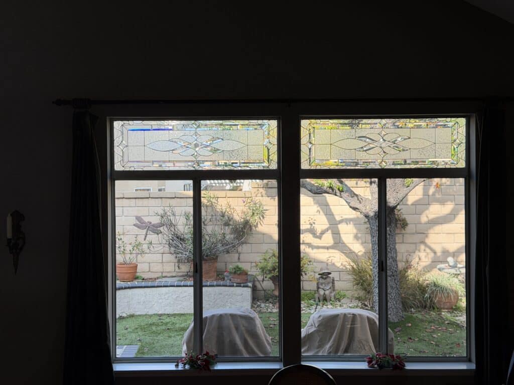 Two rectangular stained glass transom panels, each featuring a clear, textured, and beveled glass design with an intricate, symmetrical, abstract pattern of flowing lines and leaf-like shapes, incorporating subtle accents of blue and amber glass.