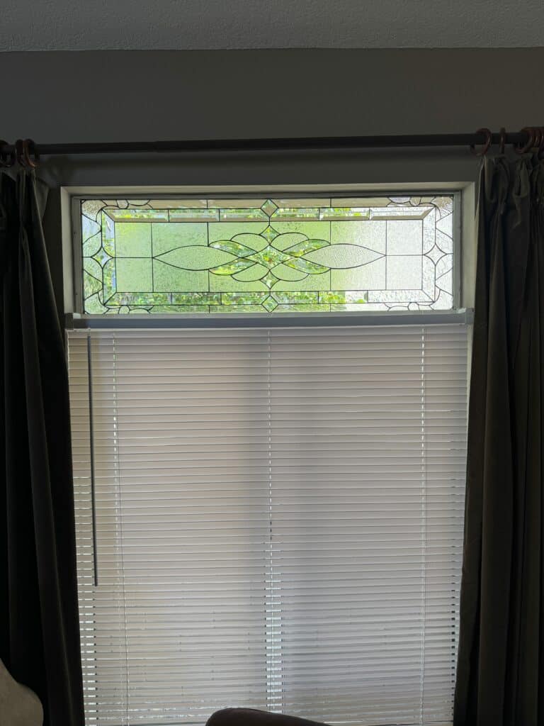 A rectangular leaded stained glass panel composed entirely of clear textured glass and bevels. The design features a prominent central horizontal scroll motif flanked by geometric rectangles and squares.