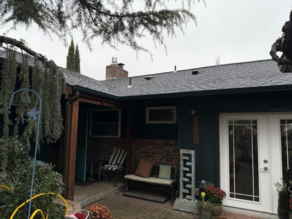 A white full-view door with clear glass panes divided by muntins, set in a house exterior with brick and dark siding.
