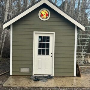 Round Rose Stained Glass Window A circular leaded stained glass window featuring a design of red roses and green leaves on a yellow background, installed in the gable of a green shed.