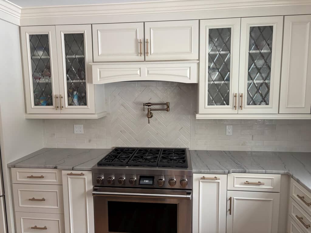 White kitchen upper cabinet doors featuring rectangular clear glass inserts with a leaded diamond pattern.