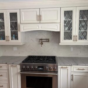 White kitchen upper cabinet doors featuring rectangular clear glass inserts with a leaded diamond pattern.