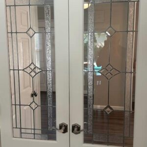 Rectangular Geometric Clear Stained Glass Double Door Inserts A pair of white double doors, each with a rectangular clear leaded glass insert. The inserts feature a geometric pattern of clear beveled glass diamonds and textured vertical panes.